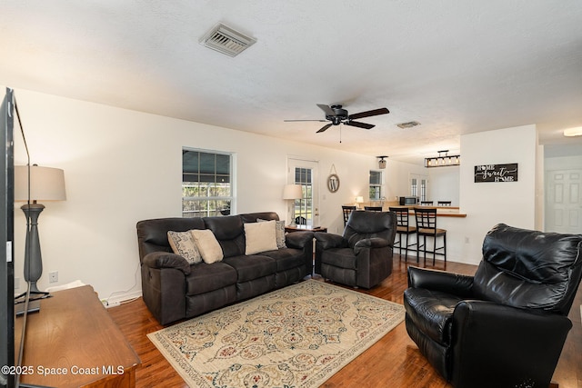 living room with ceiling fan, dark hardwood / wood-style flooring, and a textured ceiling