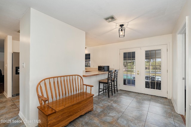 interior space featuring stainless steel refrigerator with ice dispenser, a breakfast bar area, and french doors