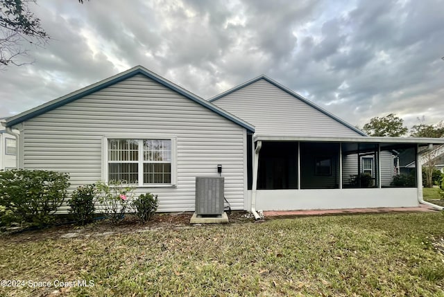 back of house with a sunroom, central AC, and a lawn