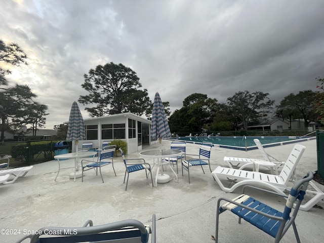 view of patio featuring a community pool and a sunroom