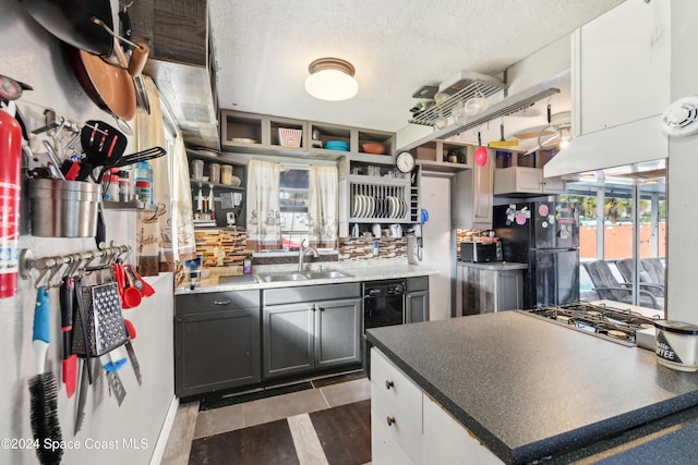 kitchen featuring gray cabinetry, a textured ceiling, black appliances, sink, and dark tile patterned flooring