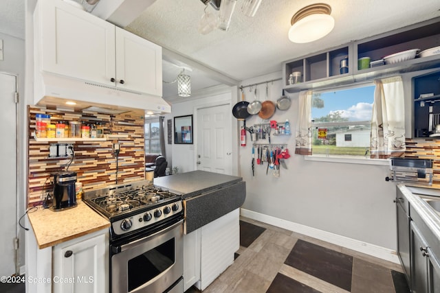 kitchen featuring white cabinetry, stainless steel range with gas cooktop, a textured ceiling, and tasteful backsplash