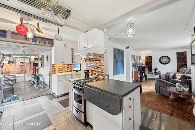 kitchen featuring white cabinets, decorative backsplash, a kitchen island, and stainless steel range with gas cooktop