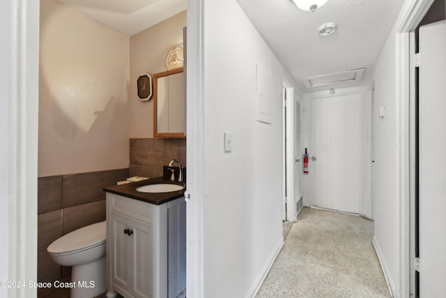 bathroom featuring vanity, toilet, and tile walls