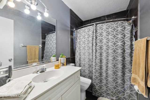 bathroom featuring vanity, toilet, a textured ceiling, and walk in shower