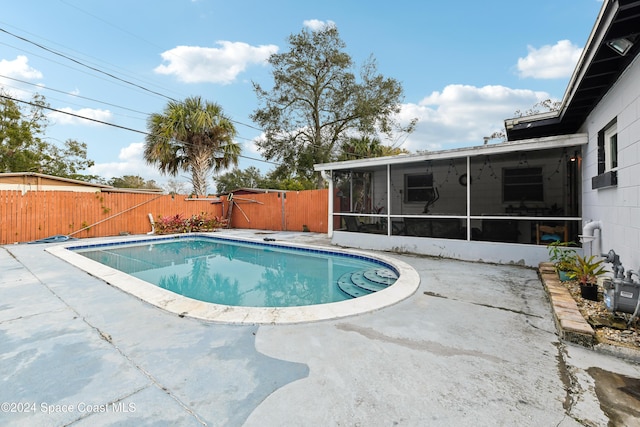 view of swimming pool with a patio area and a sunroom