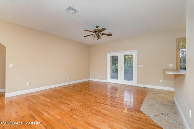 spare room with a textured ceiling, ceiling fan, light hardwood / wood-style flooring, and french doors