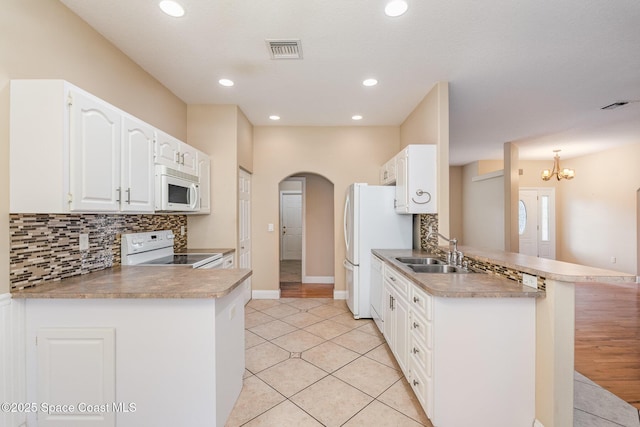 kitchen with kitchen peninsula, white appliances, sink, light tile patterned floors, and white cabinetry