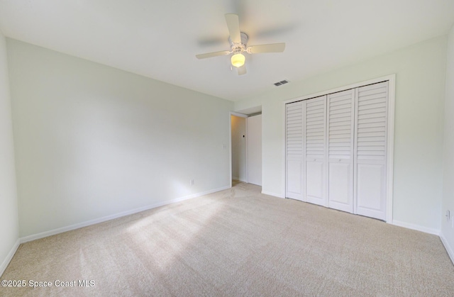 unfurnished bedroom with ceiling fan, light carpet, and a closet