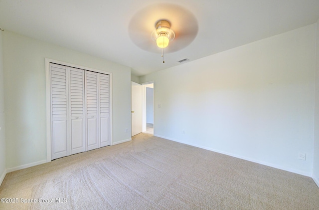 unfurnished bedroom with light carpet, a closet, and ceiling fan