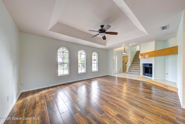 unfurnished living room featuring a raised ceiling and ceiling fan