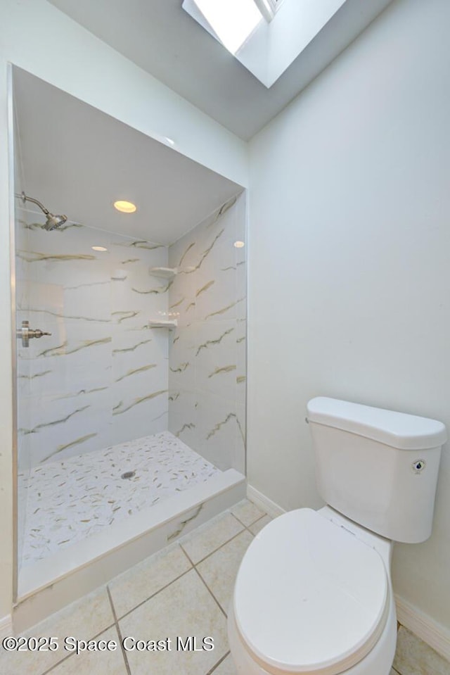 bathroom with a tile shower, a skylight, tile patterned flooring, and toilet