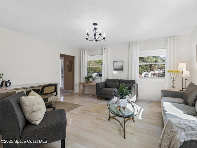 living room featuring light hardwood / wood-style flooring, a textured ceiling, and an inviting chandelier