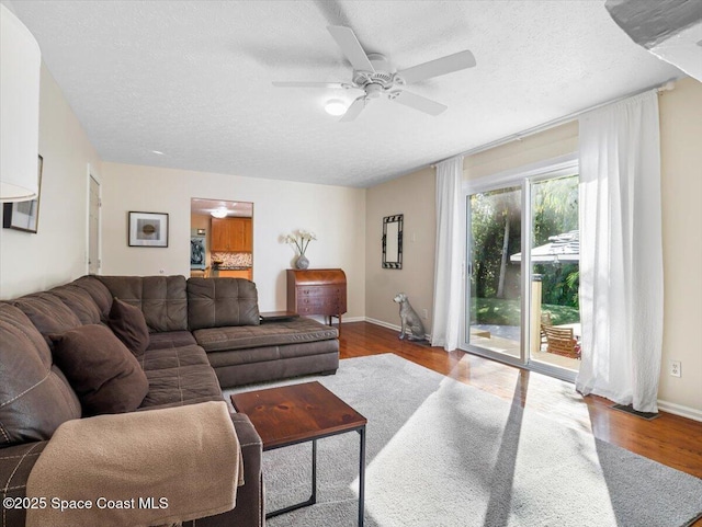 living room with ceiling fan, light hardwood / wood-style flooring, and a textured ceiling