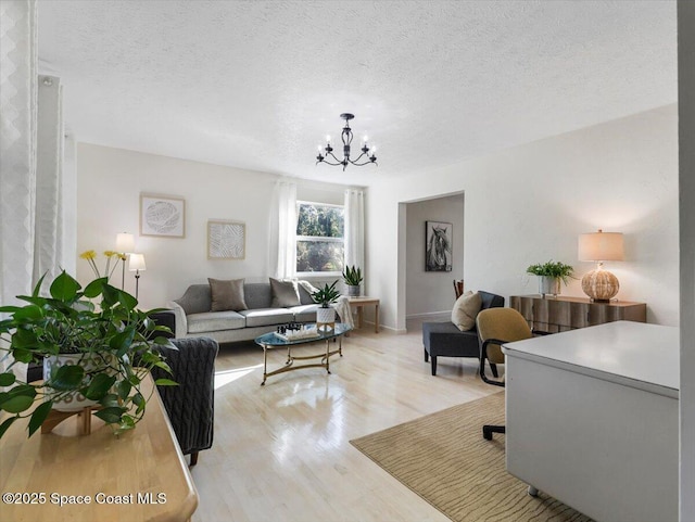 living room with a chandelier, a textured ceiling, and light hardwood / wood-style flooring