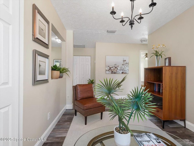 sitting room with a notable chandelier, dark hardwood / wood-style flooring, and a textured ceiling