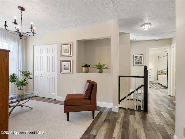 sitting room featuring dark hardwood / wood-style flooring, a textured ceiling, and a chandelier