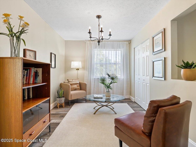 sitting room with a chandelier, a textured ceiling, and dark hardwood / wood-style floors