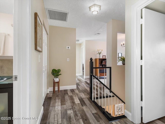 hall with a textured ceiling and dark hardwood / wood-style floors