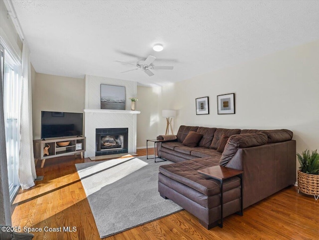 living room with ceiling fan, a textured ceiling, and hardwood / wood-style flooring