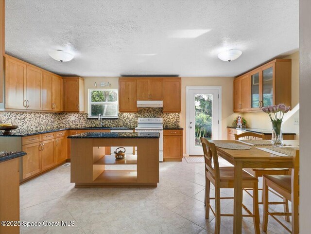 kitchen featuring backsplash, a textured ceiling, white range, dark stone countertops, and a center island