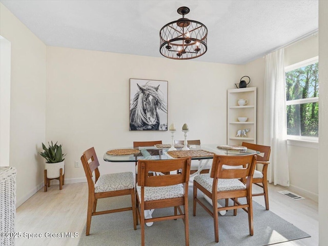 dining room featuring plenty of natural light, a notable chandelier, and light wood-type flooring