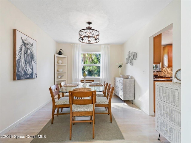 dining room featuring a textured ceiling, light hardwood / wood-style flooring, and a notable chandelier