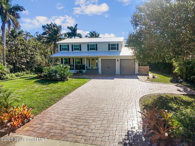 view of front of property with covered porch, a garage, and a front yard