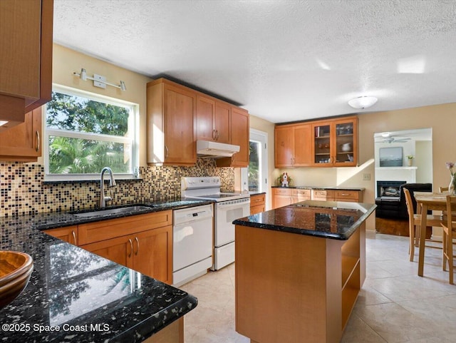 kitchen featuring a textured ceiling, a kitchen island, white appliances, and sink