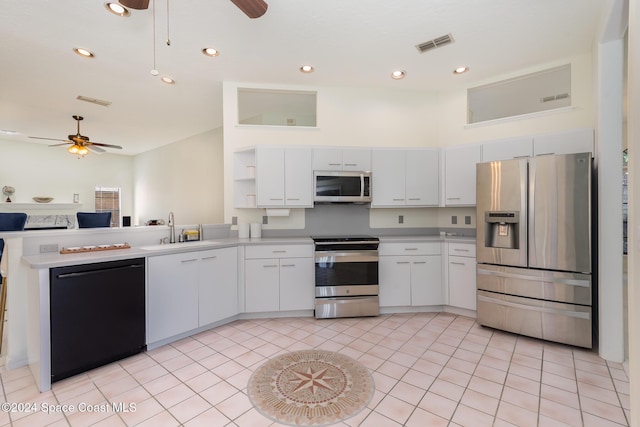 kitchen with stainless steel appliances, ceiling fan, sink, light tile patterned floors, and white cabinets