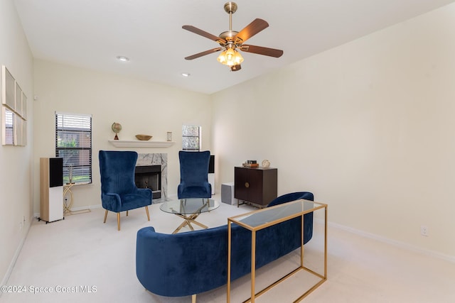 carpeted living room with ceiling fan and a premium fireplace