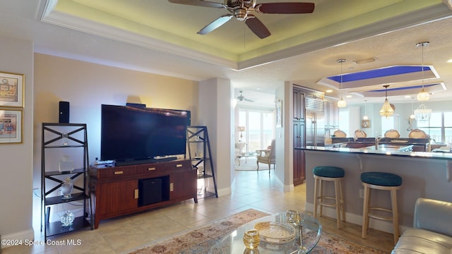 tiled living room featuring ceiling fan, a raised ceiling, and ornamental molding