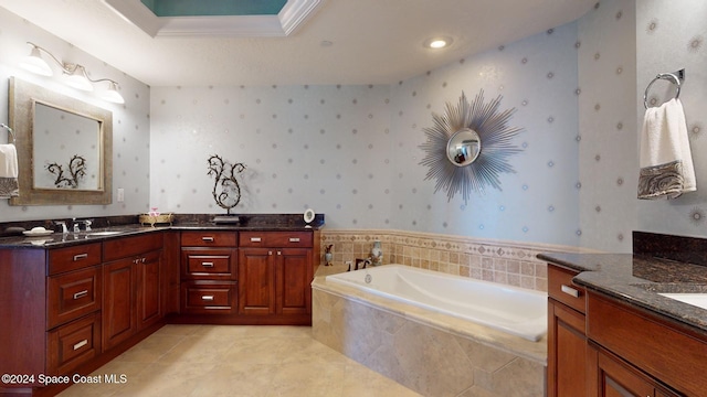 bathroom with tile patterned floors, ornamental molding, vanity, a tray ceiling, and a relaxing tiled tub