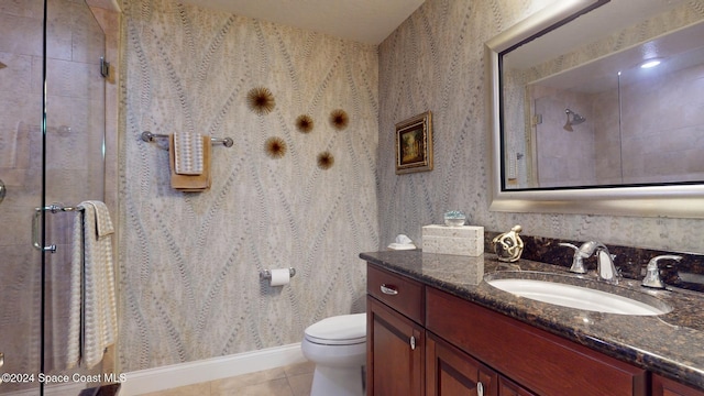 bathroom featuring tile patterned flooring, vanity, toilet, and an enclosed shower