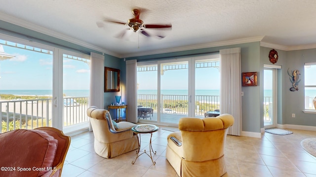 interior space featuring a water view, ceiling fan, ornamental molding, a textured ceiling, and a healthy amount of sunlight