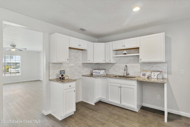 kitchen with white cabinets, light stone countertops, and sink