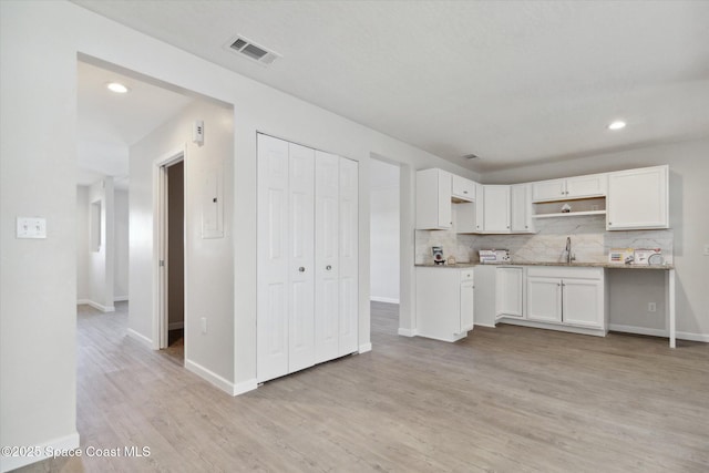 kitchen featuring backsplash, white cabinetry, sink, and light wood-type flooring