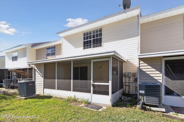 rear view of property with central AC unit, a lawn, and a sunroom