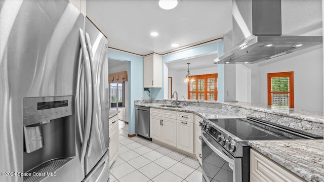 kitchen with wall chimney range hood, sink, light tile patterned floors, appliances with stainless steel finishes, and white cabinetry