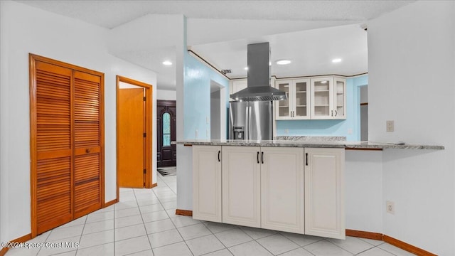 kitchen featuring stainless steel fridge with ice dispenser, island range hood, light stone countertops, and white cabinetry