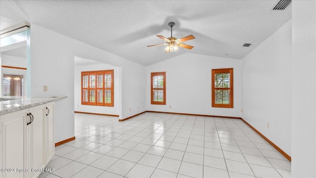 interior space featuring ceiling fan, lofted ceiling, a textured ceiling, and light tile patterned floors