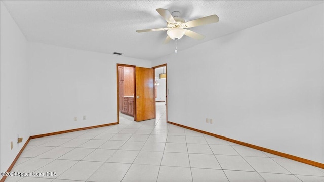 tiled empty room with ceiling fan and a textured ceiling