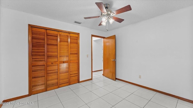 unfurnished bedroom with ceiling fan, a closet, light tile patterned flooring, and a textured ceiling