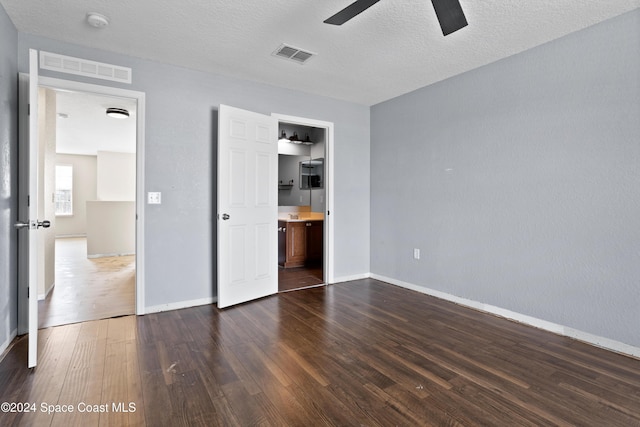 unfurnished bedroom featuring a textured ceiling, ceiling fan, dark wood-type flooring, and a closet