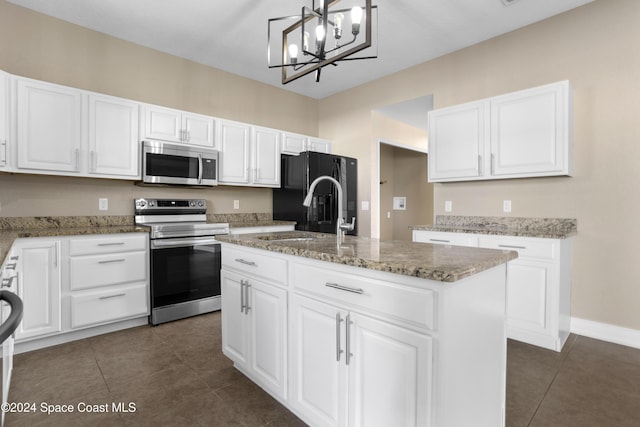 kitchen with appliances with stainless steel finishes, a notable chandelier, white cabinets, hanging light fixtures, and an island with sink