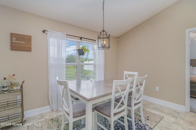 dining space with vaulted ceiling, baseboards, and a chandelier