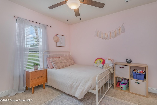 bedroom featuring baseboards, light colored carpet, and a ceiling fan