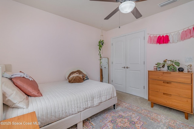 bedroom with a closet, visible vents, light colored carpet, and ceiling fan