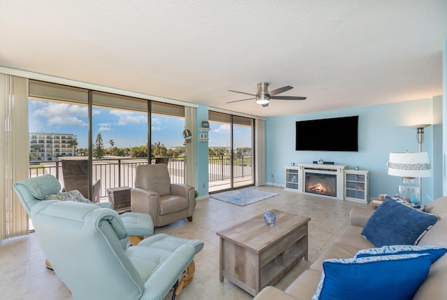 living room with floor to ceiling windows, ceiling fan, light tile patterned flooring, and a textured ceiling