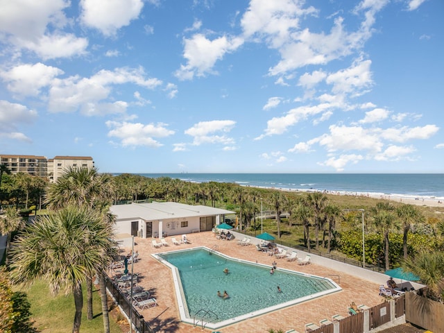 view of swimming pool with a water view, a patio, and a view of the beach